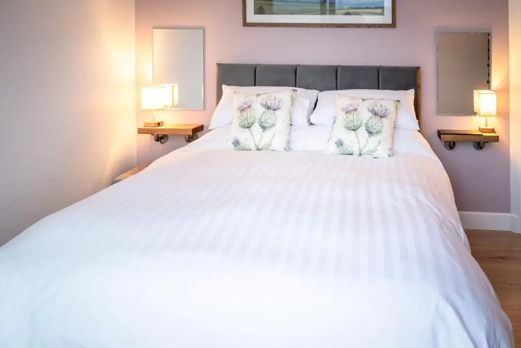 a bedroom with a white bed with flowers on the pillows at Bennachie Lodge in Huntly