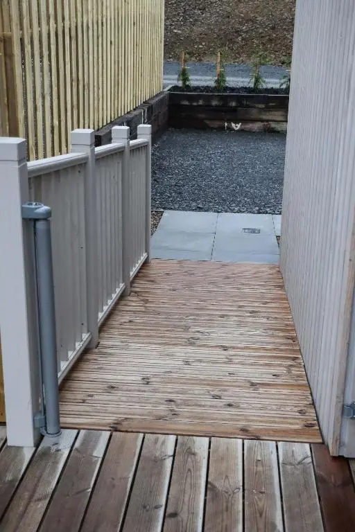 a wooden porch with a fence and a wooden floor at Bennachie Lodge in Huntly