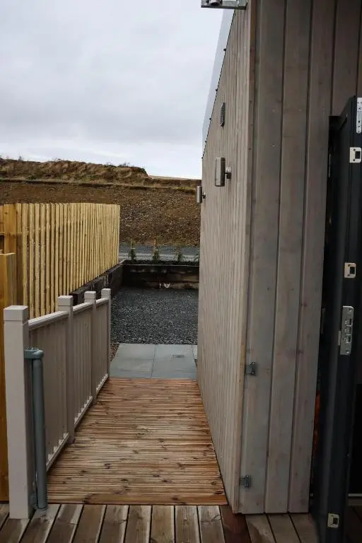 a wooden walkway leading to a building with a fence at Bennachie Lodge in Huntly