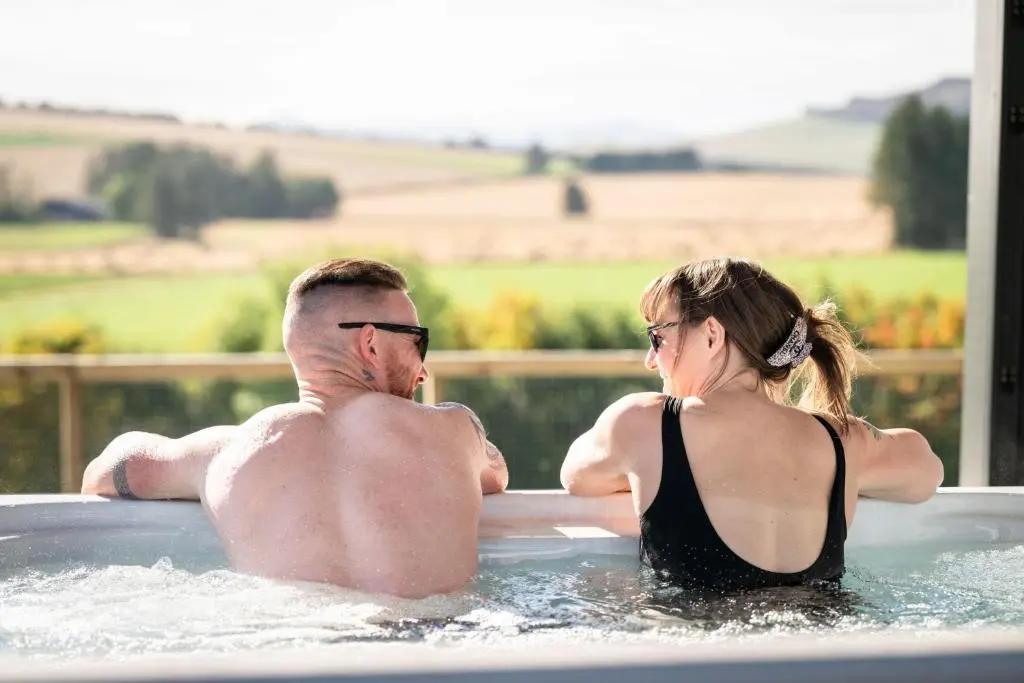 a man and a woman sitting in a hot tub at Bennachie Lodge in Huntly