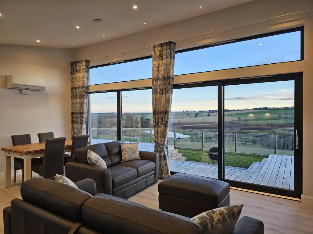 a living room with a couch and a large window at Woodland Lodge in Huntly