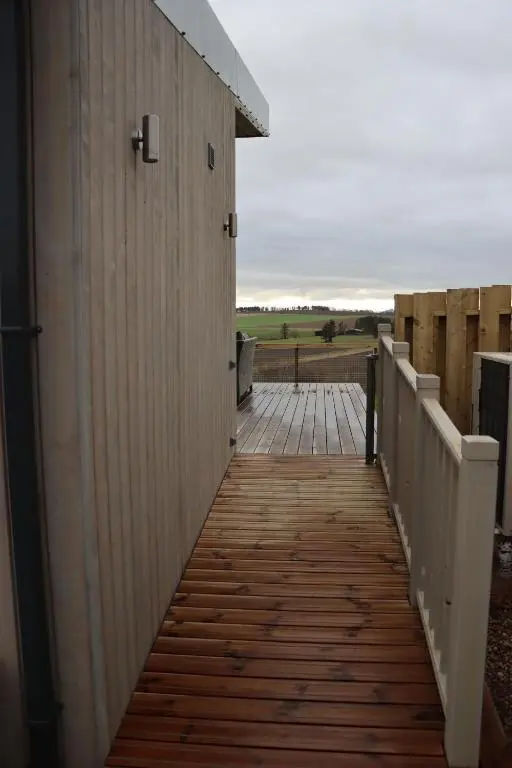 a wooden walkway leading to a building with a field in the background at Woodland Lodge in Huntly