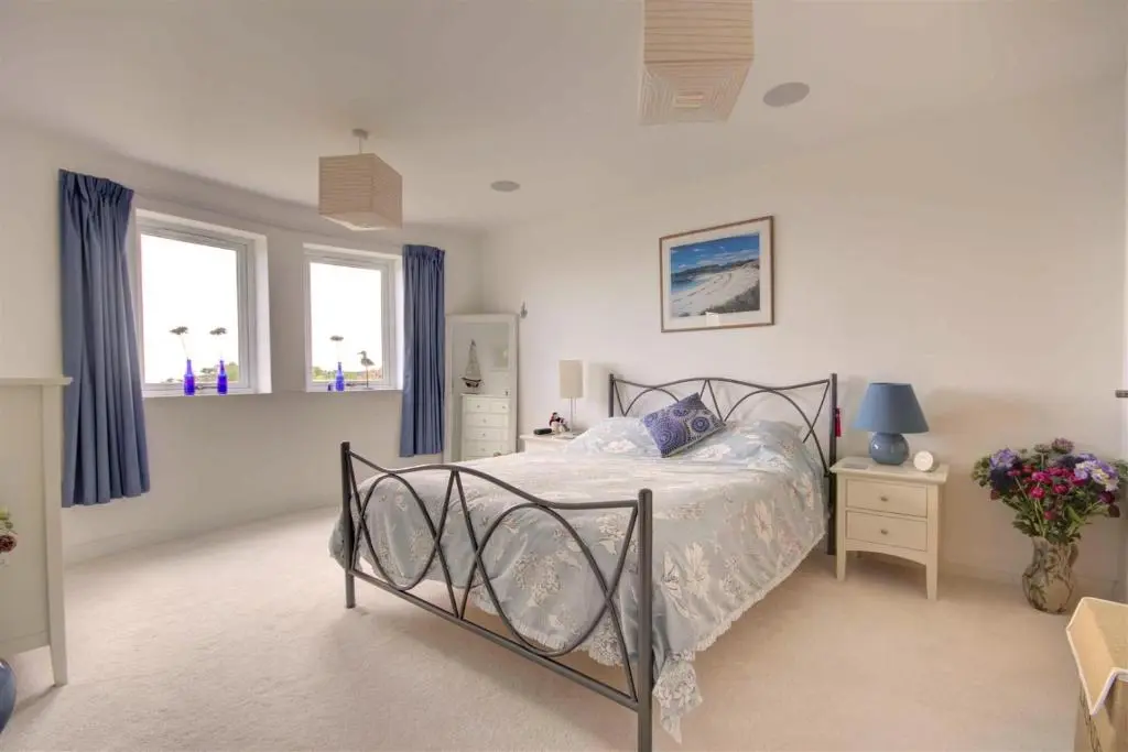 a bedroom with a bed and two windows at The Old Coastguard Station in Helmsdale