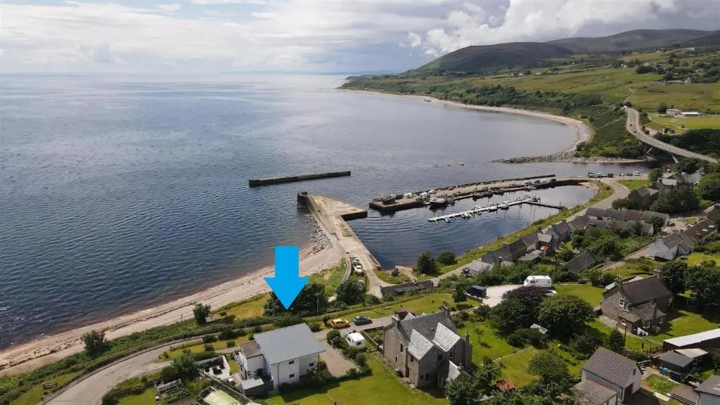 an aerial view of a house on the shore of a lake at The Old Coastguard Station in Helmsdale