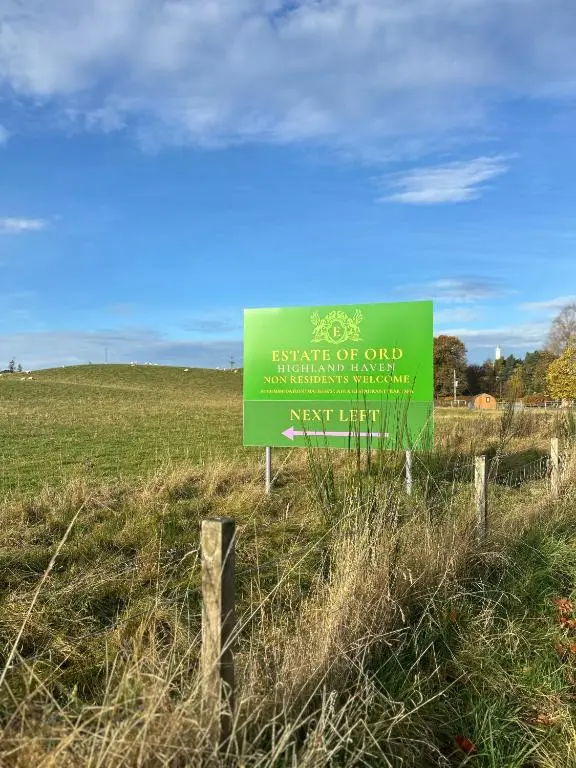 a green sign in the middle of a field at Estate Of Ord in Muir of Ord