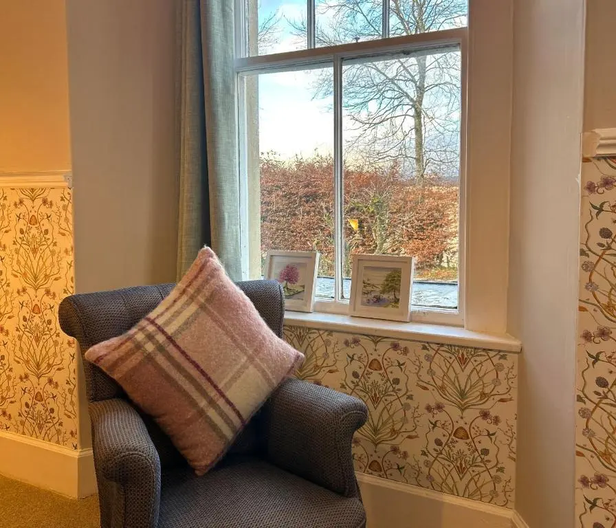 a chair sitting in front of a window with two picture frames at Estate Of Ord in Muir of Ord