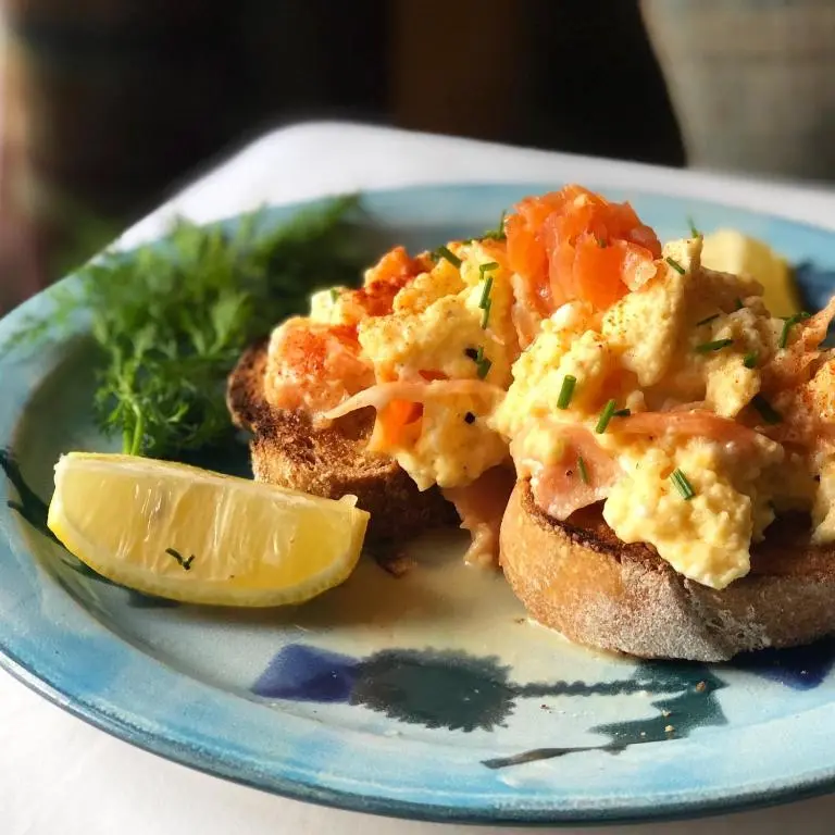 a plate of food with eggs on bread with a lemon wedge at Runnymede House in Inverness