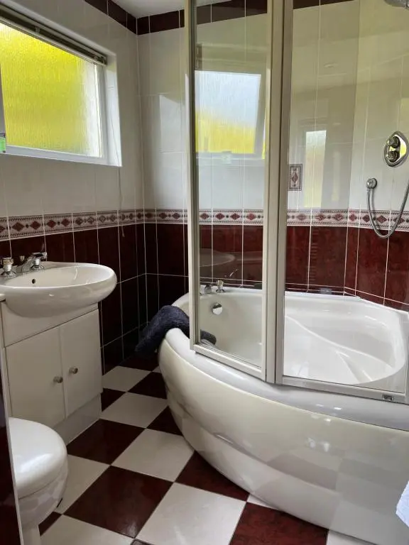 a bathroom with a tub and a toilet and a sink at Runnymede House in Inverness