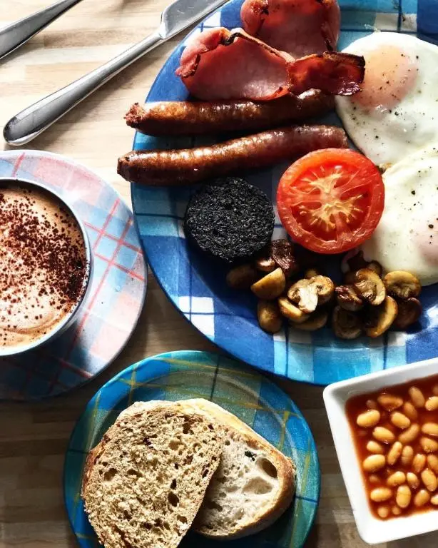 a table with two plates of breakfast foods and a cup of coffee at Runnymede House in Inverness