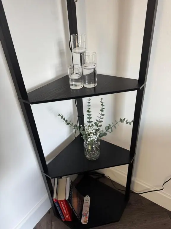 a black shelf with two glasses and a vase with flowers at Lorna Doune in Port Elphinstone