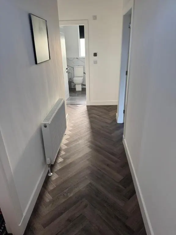 a bathroom with a hallway with a toilet and wooden floors at Lorna Doune in Port Elphinstone