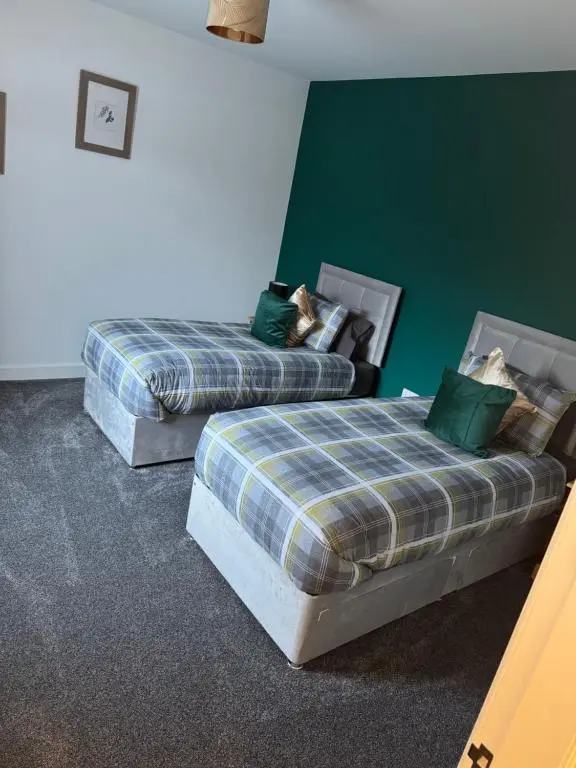 two beds in a room with green walls at Lorna Doune in Port Elphinstone
