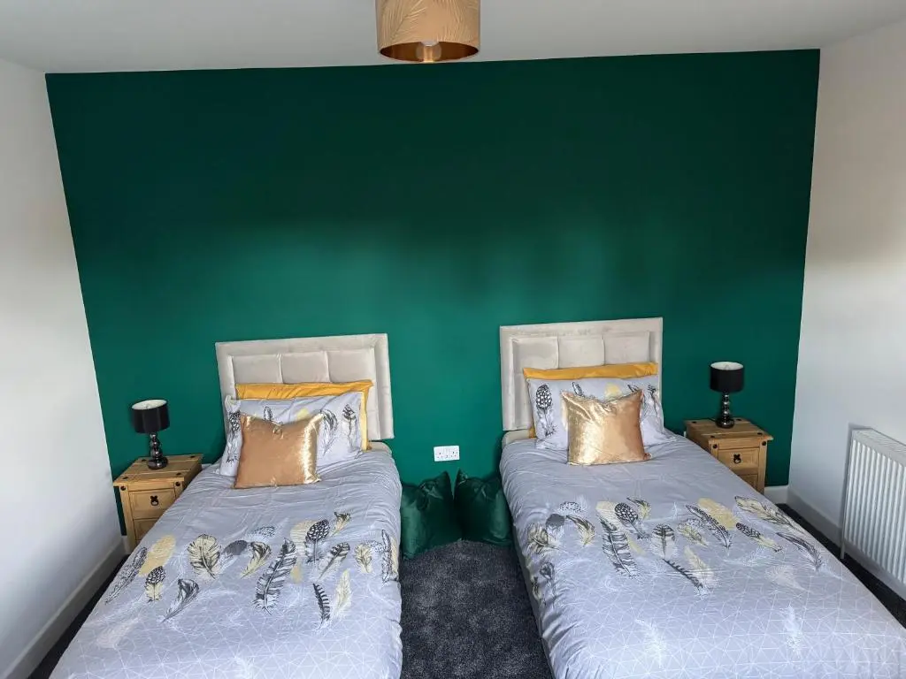 two beds in a room with a green wall at Lorna Doune in Port Elphinstone
