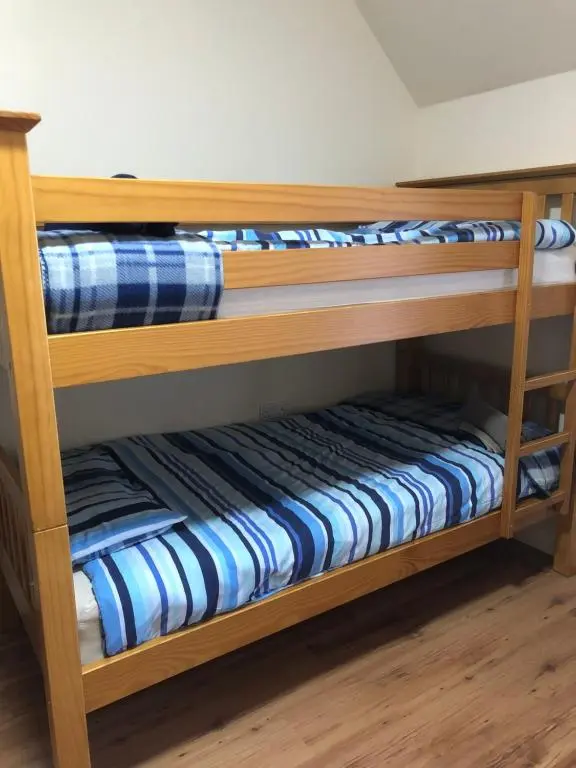 two wooden bunk beds with blue and white sheets at 1 Lochness Rooms&Hostel in Drumnadrochit