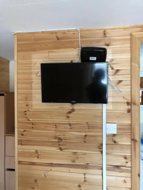 a flat screen tv hanging on a wooden wall at 1 Lochness Rooms&Hostel in Drumnadrochit
