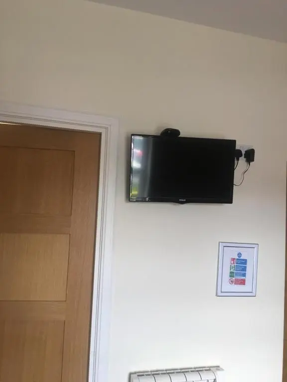 a flat screen tv hanging on a wall next to a door at 1 Lochness Rooms&Hostel in Drumnadrochit