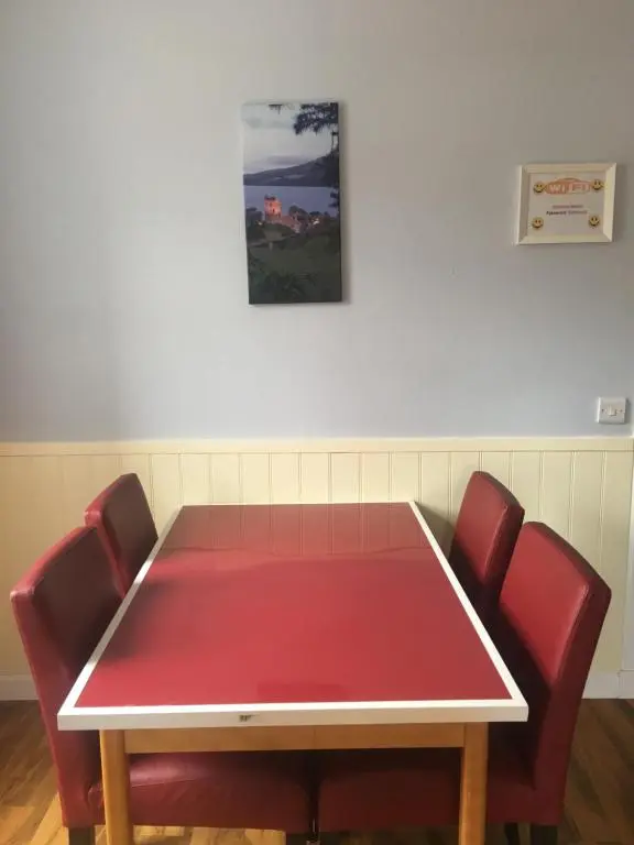 a ping pong table in a room with red chairs at 1 Lochness Rooms&Hostel in Drumnadrochit