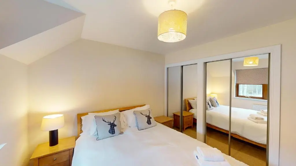 a bedroom with a bed and a mirror at Lairig Ghru Lodge in Aviemore