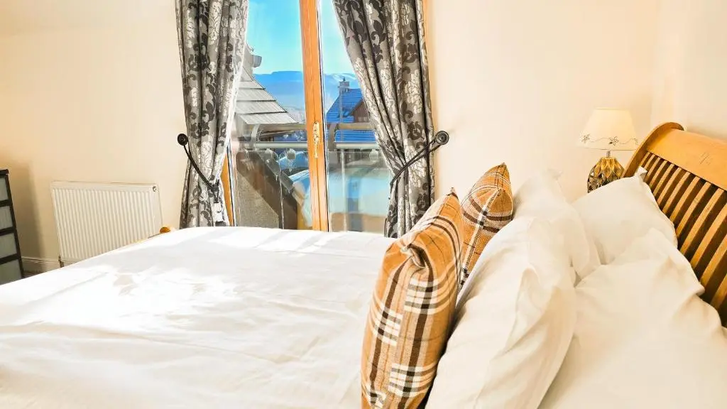 a bedroom with a white bed and a window at Lairig Ghru Lodge in Aviemore