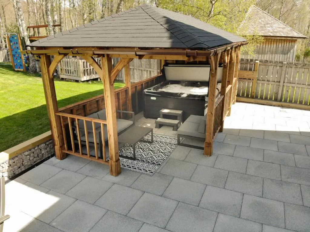 a wooden gazebo with a grill in a yard at Lairig Ghru Lodge in Aviemore