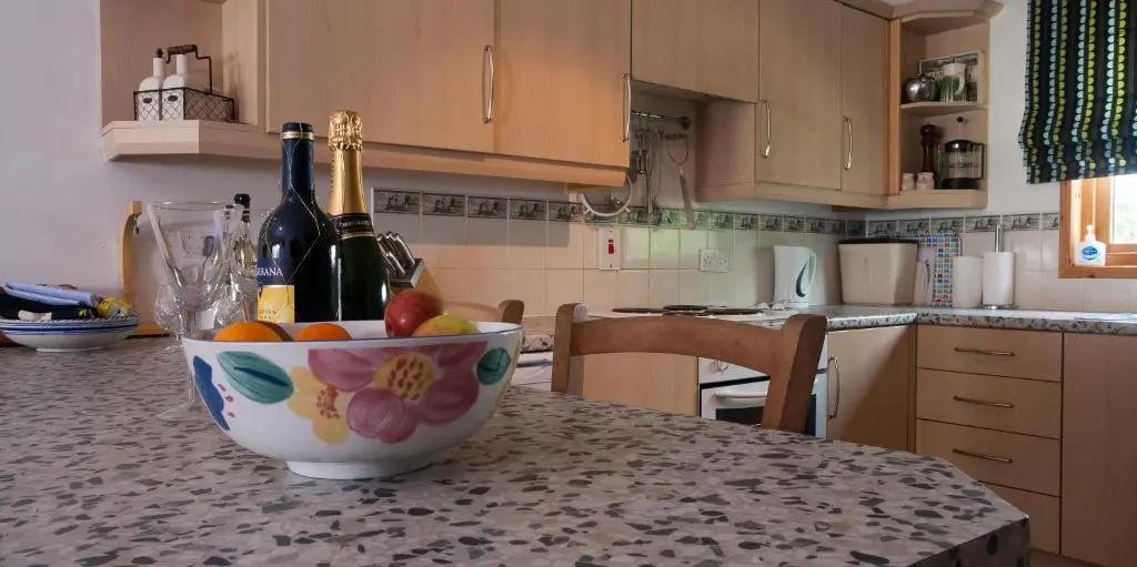 a kitchen with a bowl of fruit on a counter at Heath Cottage, Tranquil Cottage by the Woods in Boat of Garten
