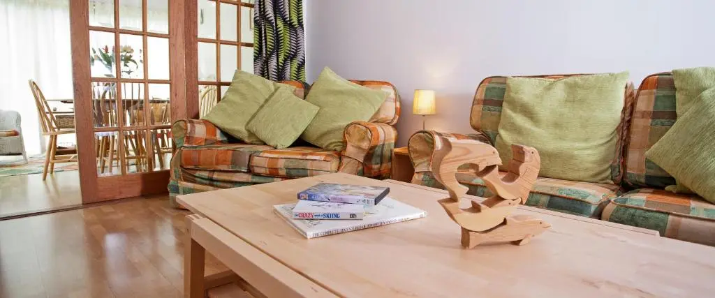 a living room with a table with a book on it at Heath Cottage, Tranquil Cottage by the Woods in Boat of Garten