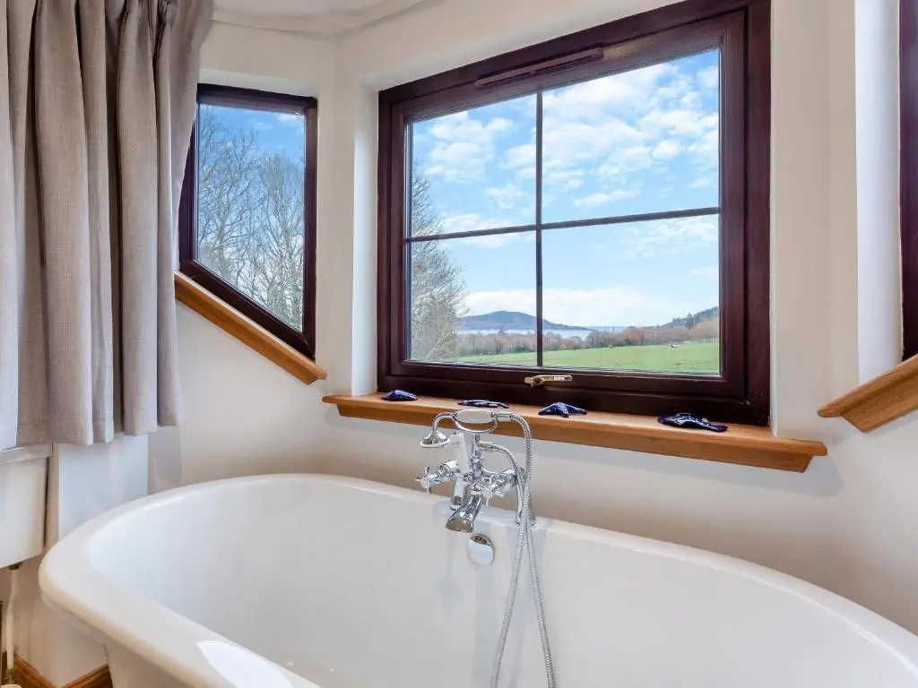 a bathroom with a bath tub and a window at Bunchrew Farm Cottage in Inverness