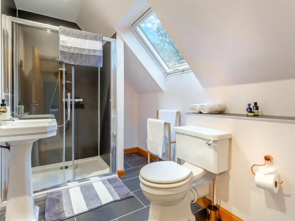 a bathroom with a toilet and a shower and a sink at Bunchrew Farm Cottage in Inverness