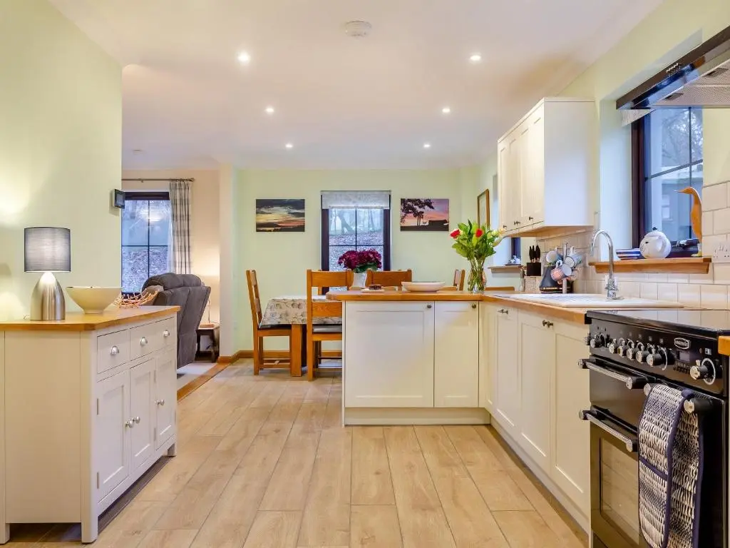 a kitchen with white cabinets and a dining room at Bunchrew Farm Cottage in Inverness