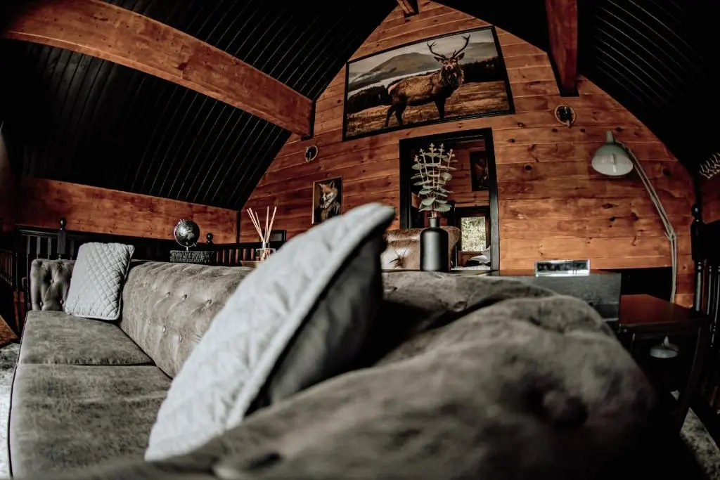 a living room with a couch and a deer on the wall at Lodges On Loch Ness in Inverness