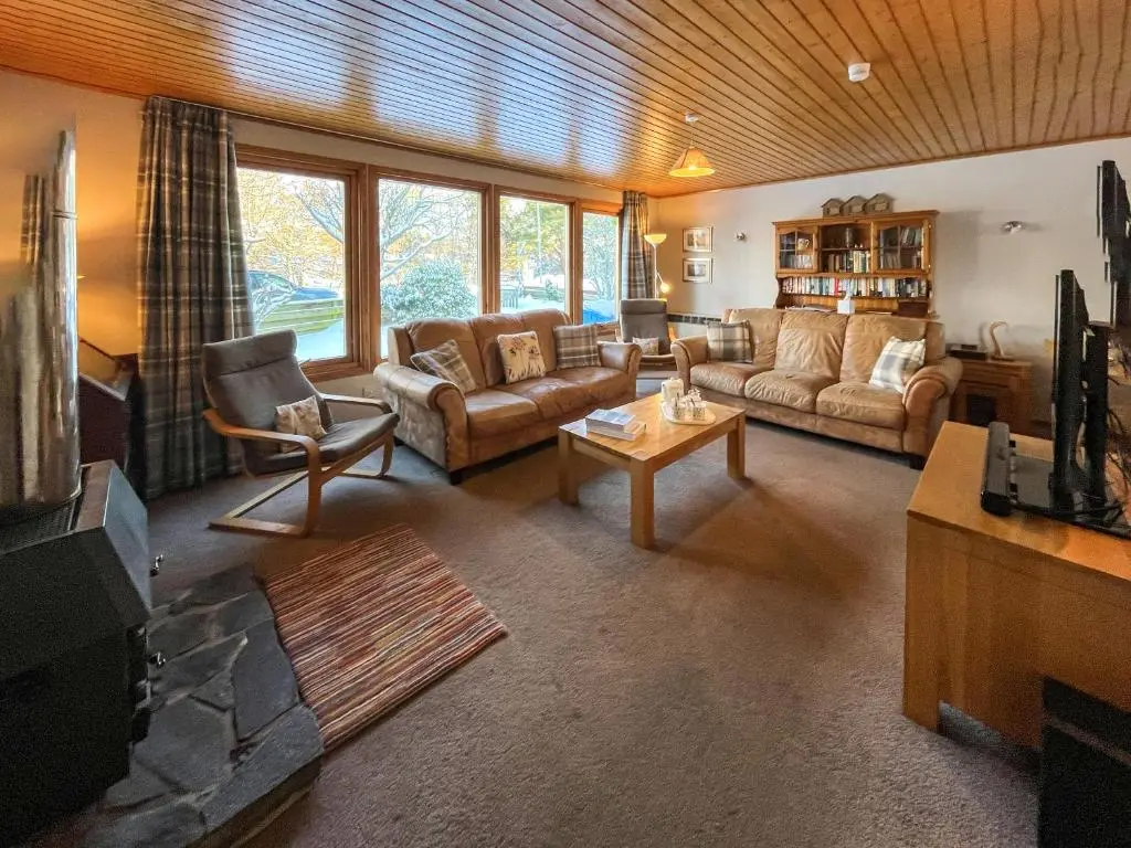a large living room with couches and a tv at Lorien Cottage in Nethy Bridge