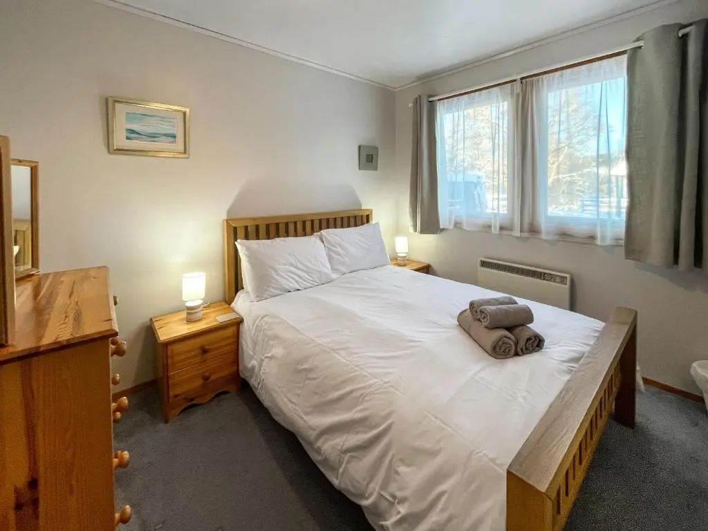 a bedroom with a bed with a bag on it at Lorien Cottage in Nethy Bridge