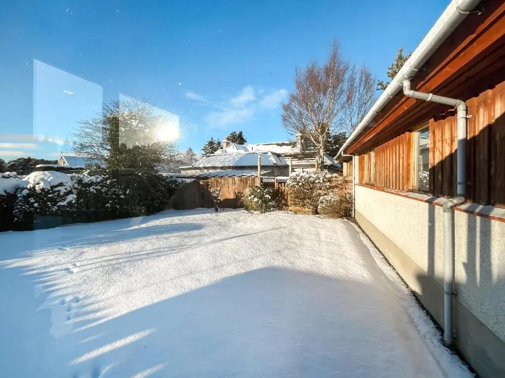 a driveway covered in snow next to a house at Lorien Cottage in Nethy Bridge