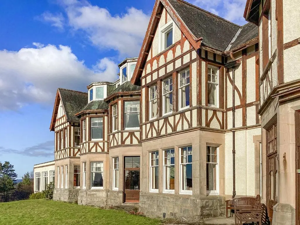 a large house with a green lawn in front of it at The Carnegie Rooms At Aultnagar Lodge - Uk48666 in Lairg