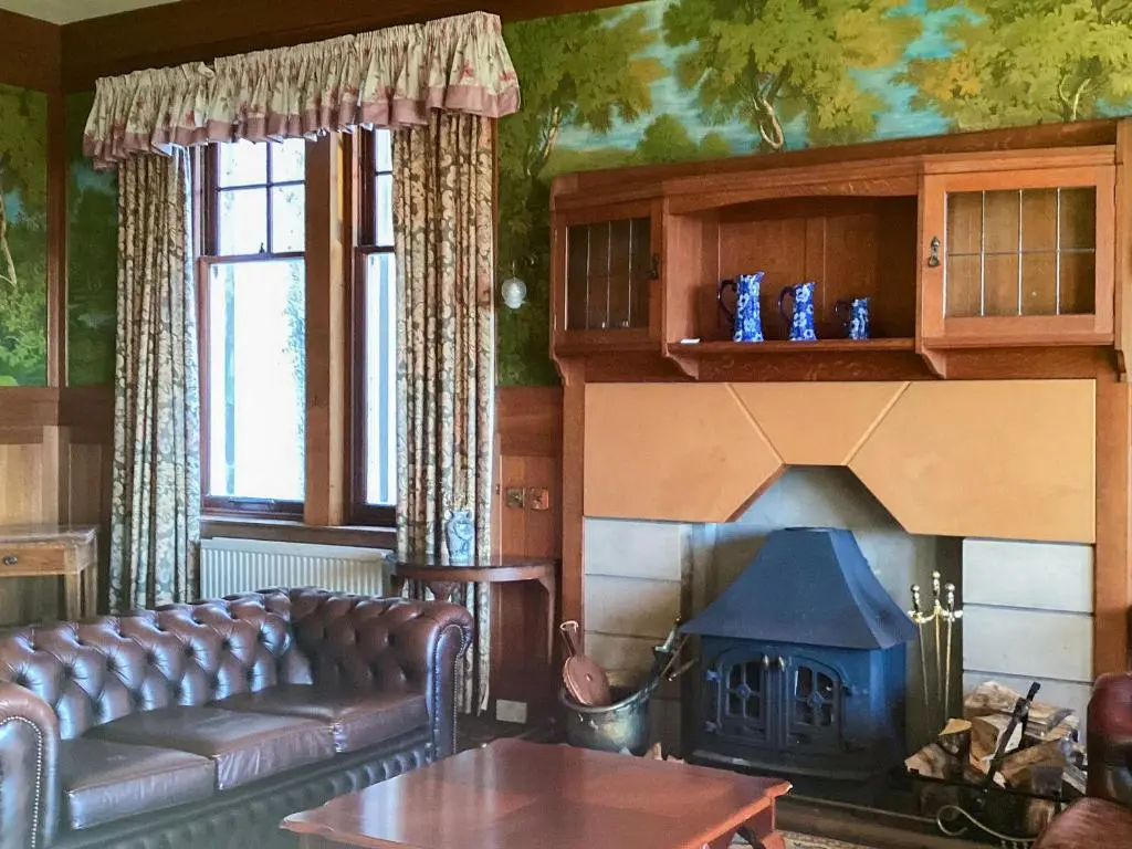 a living room with a couch and a fireplace at The Carnegie Rooms At Aultnagar Lodge - Uk48666 in Lairg