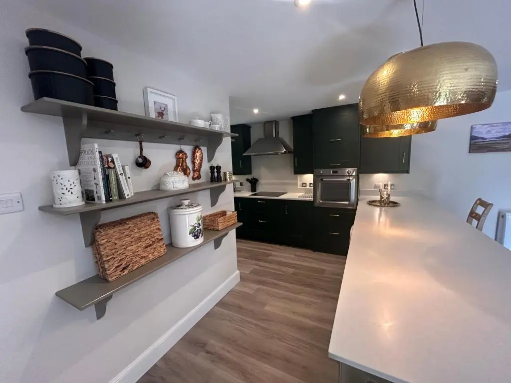 a kitchen with black cabinets and a white counter top at Aldernaig Mill in Invergarry