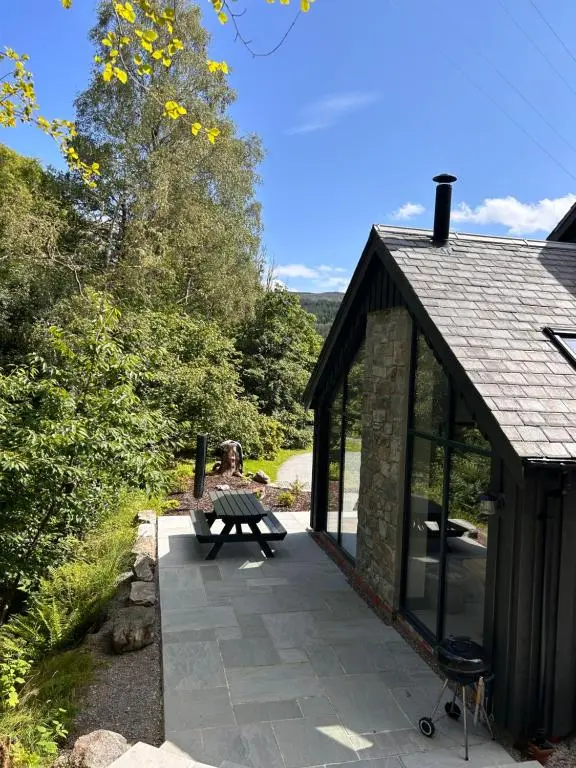 a small cabin with a bench on a patio at Aldernaig Mill in Invergarry