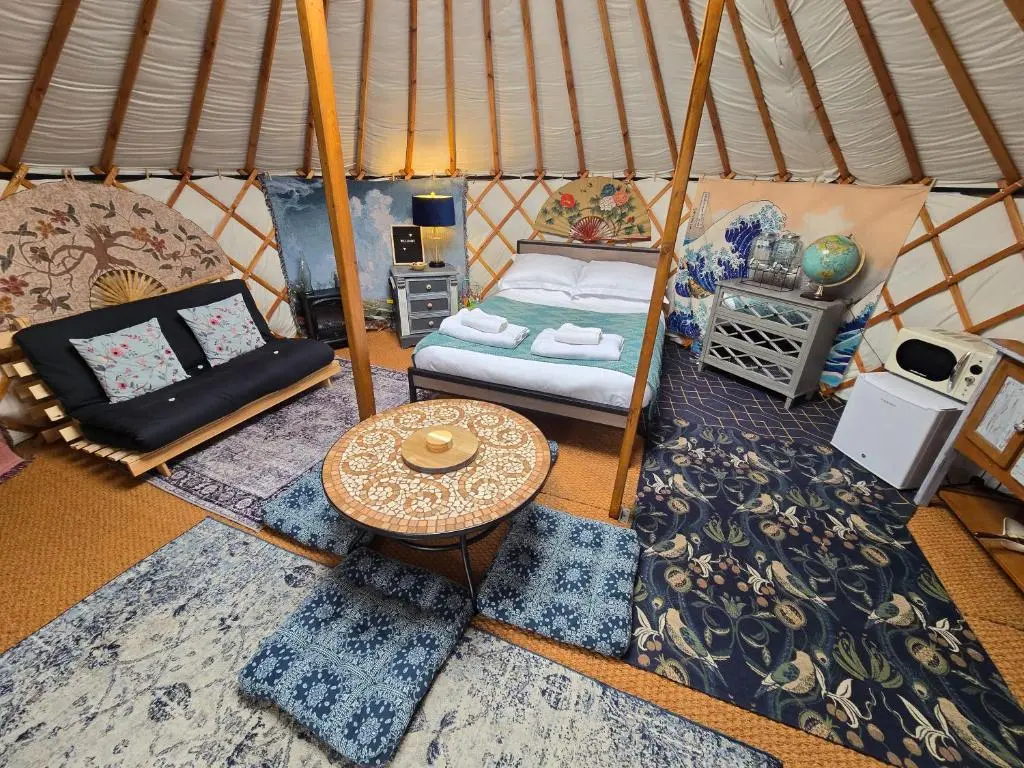 a room with a bed and a table in a yurt at Rainbow's End Yurts in Dornoch