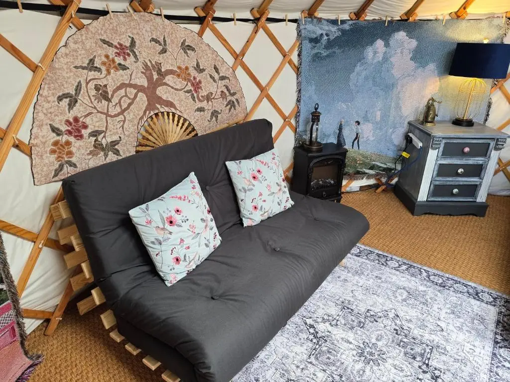 a living room with a black couch with two pillows at Rainbow's End Yurts in Dornoch