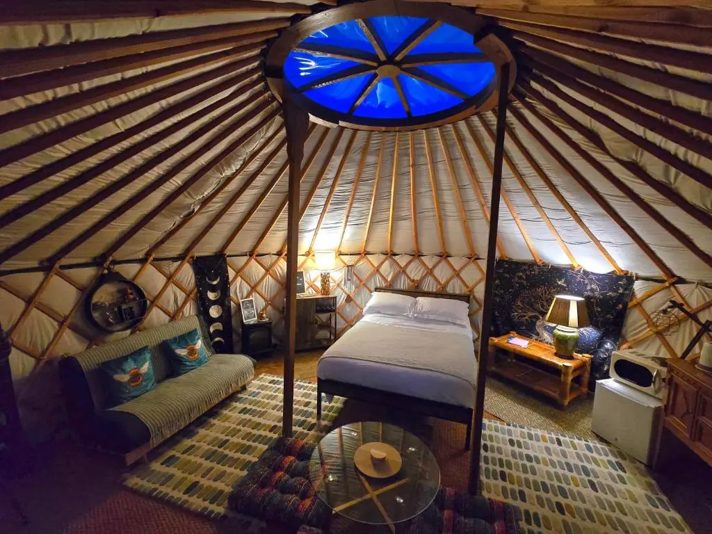 a room with a bed and a table in a yurt at Rainbow's End Yurts in Dornoch