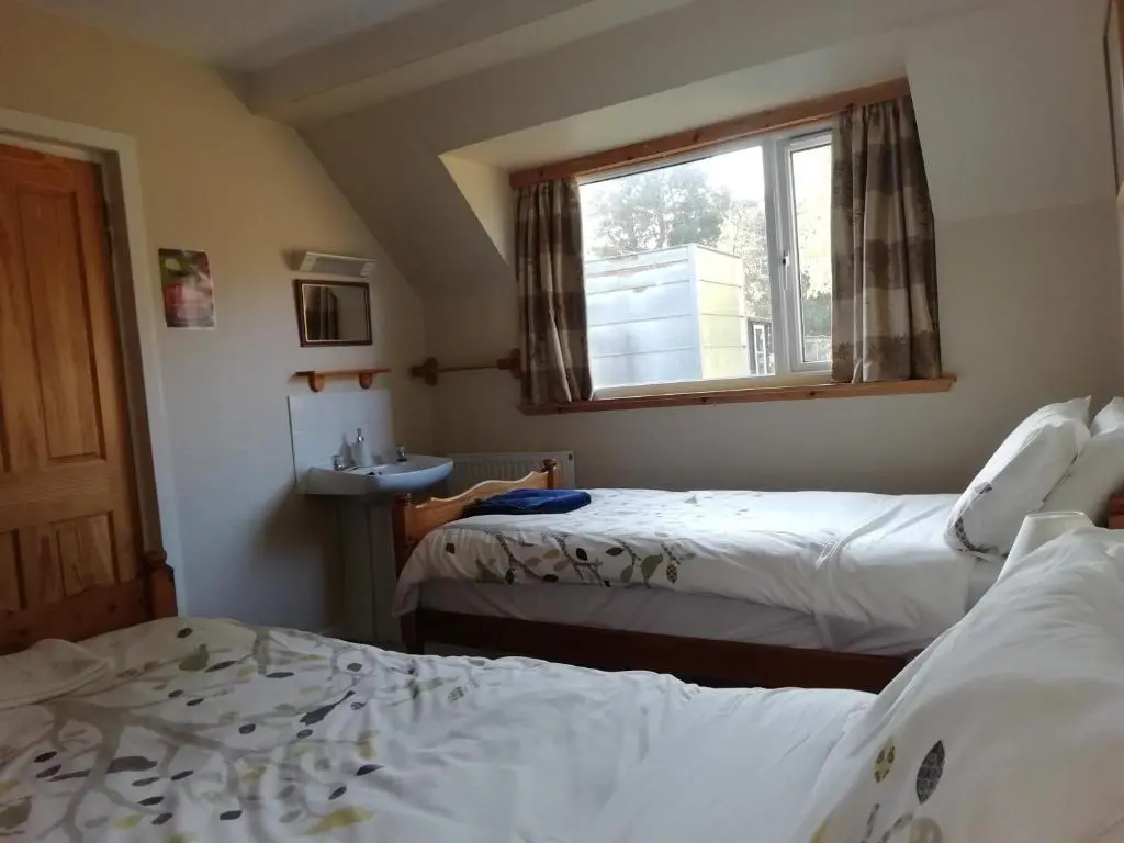 a bedroom with two beds and a window and a sink at Fraoch Lodge in Boat of Garten