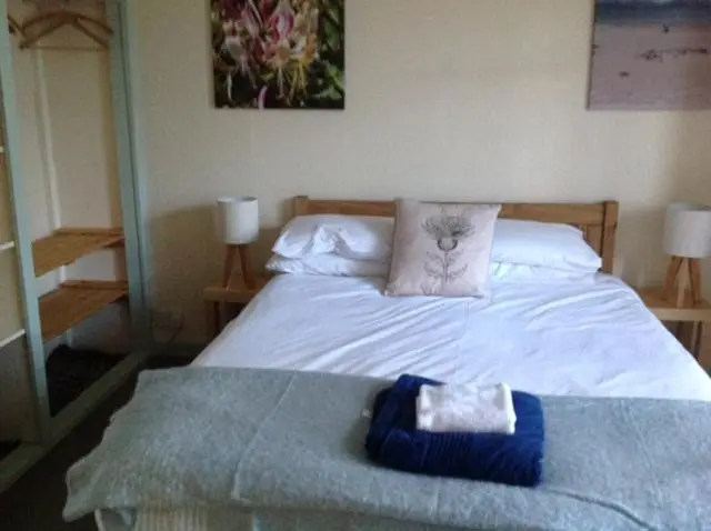 a bedroom with a white bed with a blue towel on it at Fraoch Lodge in Boat of Garten