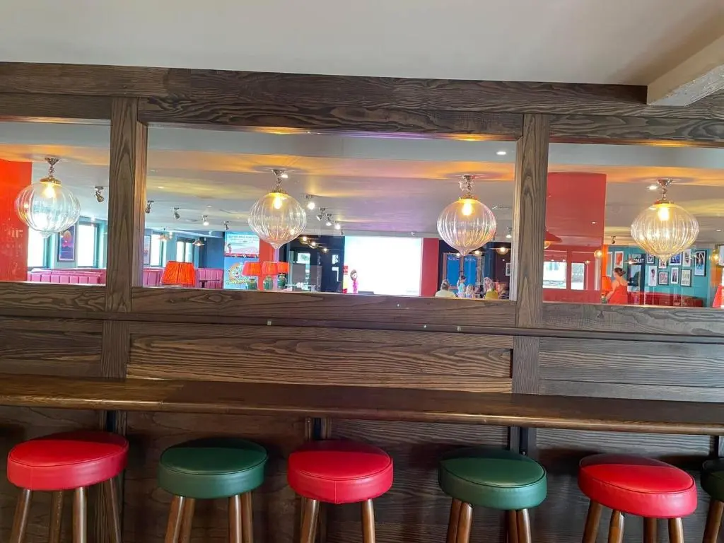 a bar with red and green stools in a restaurant at Ballies Retreat in Lossiemouth