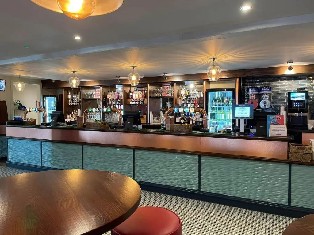 a bar in a restaurant with a table and chairs at Ballies Retreat in Lossiemouth