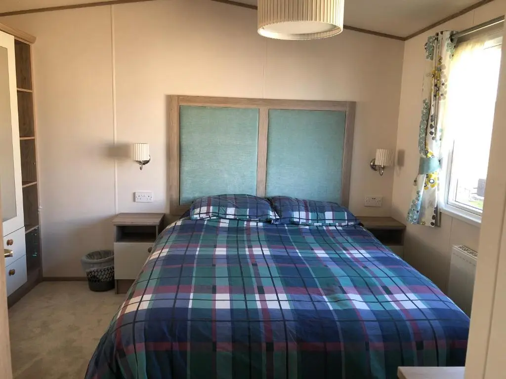 a bedroom with a bed with a plaid blanket at Ballies Retreat in Lossiemouth