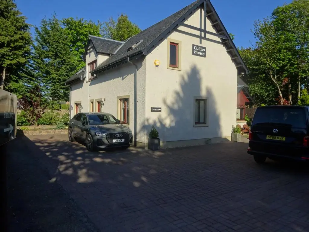 a car parked in front of a white building at Culliss House B&B in Inverness