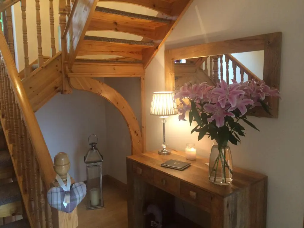 a room with a staircase and a table with a vase of flowers at Culliss House B&B in Inverness