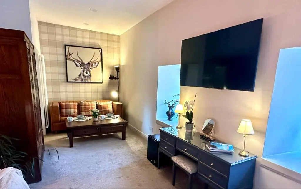 a living room with a dresser with a television on the wall at Beechtree Cottage, Cairngorm Suite, Kirkmichael in Blairgowrie