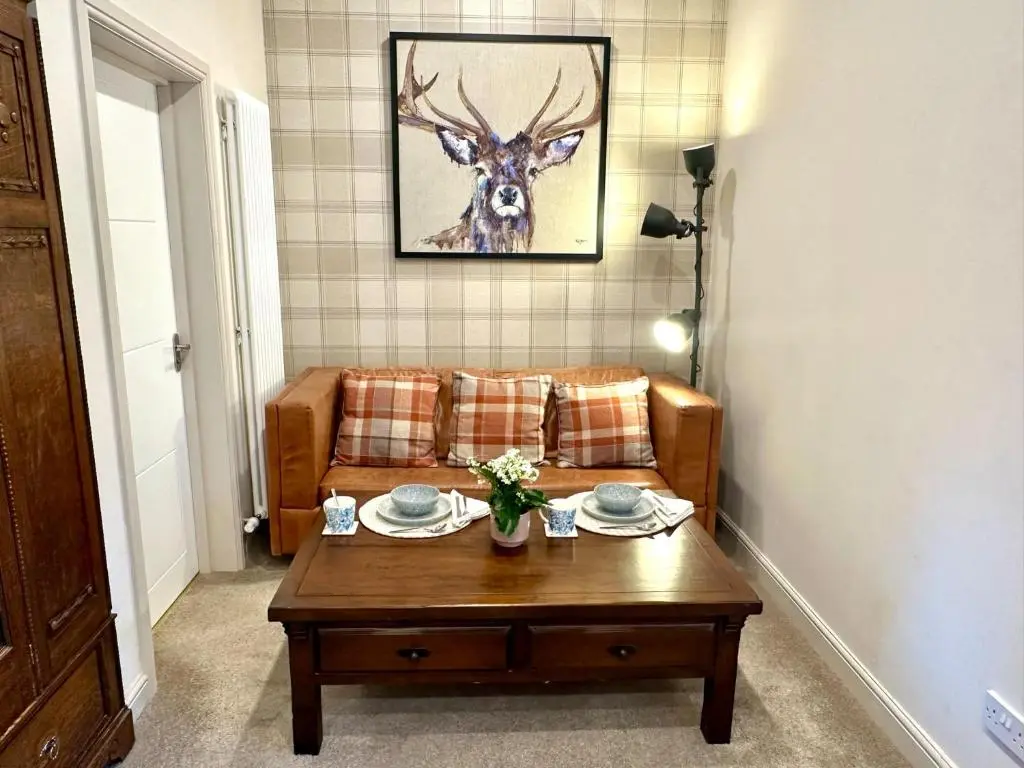 a living room with a couch and a table at Beechtree Cottage, Cairngorm Suite, Kirkmichael in Blairgowrie