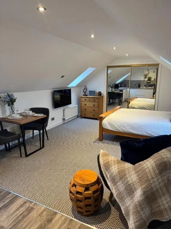 a bedroom with a bed and a table and a tv at An Cuiltheann Apartment in Turriff